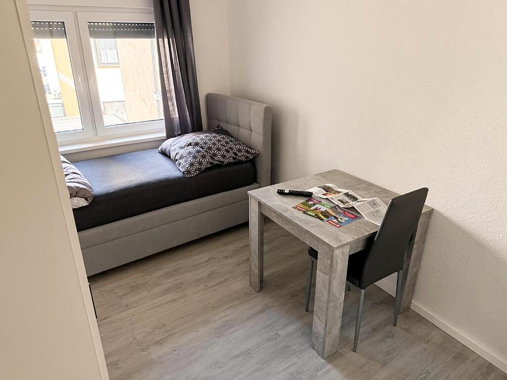 Zimmer mit Bett, Schreibtisch und Fenster zur Stadt